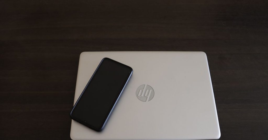 Close-up of a smartphone resting on an HP laptop, symbolizing modern technology integration.