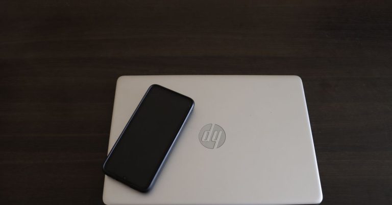 Close-up of a smartphone resting on an HP laptop, symbolizing modern technology integration.