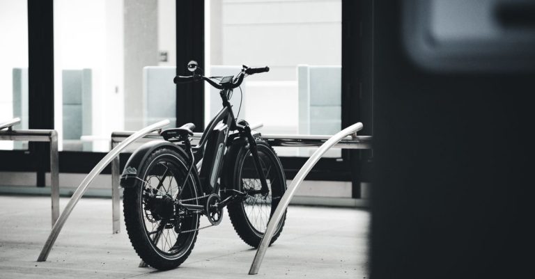 Black and white image of an electric bicycle parked indoors in an urban environment.