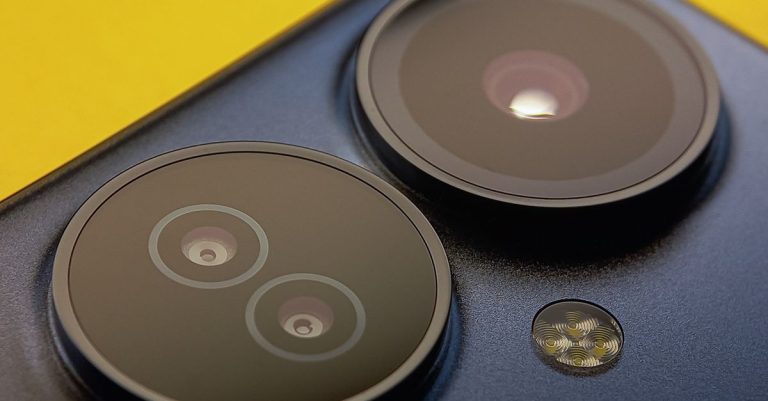 Extreme close-up of smartphone camera lenses with vibrant yellow background, showcasing modern technology.