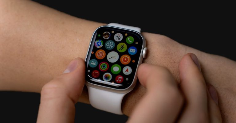 Close-up of person interacting with a smartwatch displaying apps on a dark background.