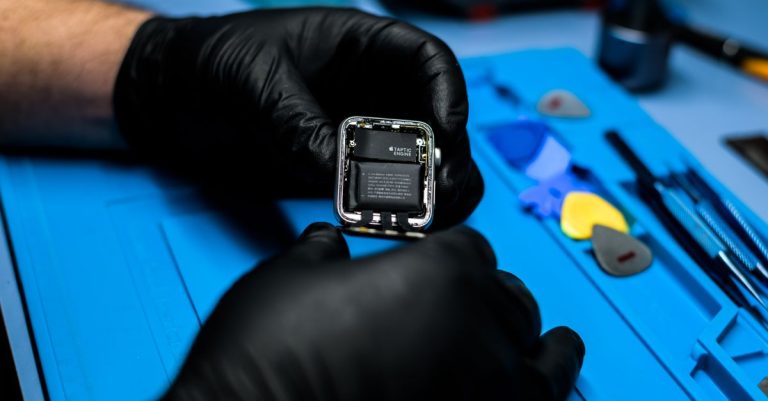 Technician disassembling smartwatch with precision tools in a repair workshop.