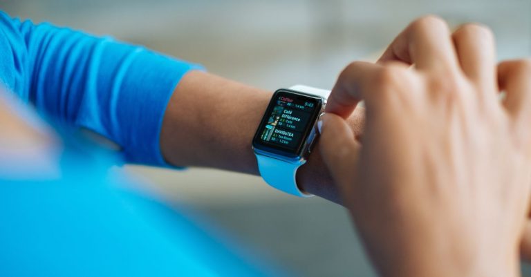 Person interacting with a smartwatch, showing a fitness application on the screen.