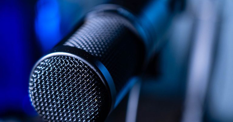 Detailed close-up of a professional studio microphone with a blurred blue background.
