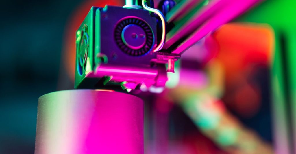 Close-up of a 3D printer in action under neon lighting, capturing vibrant colors and modern tech ambiance.