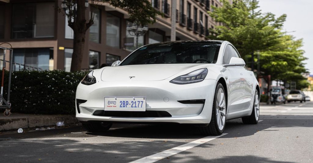 A sleek white Tesla Model 3 parked on a city street under trees, showcasing modern automotive design.
