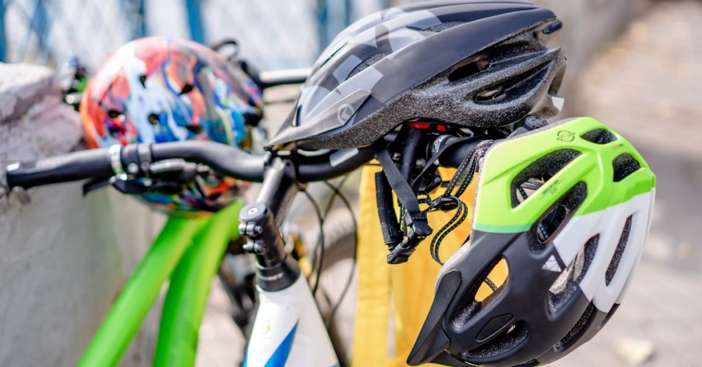 Close-up of brightly colored bicycle helmets resting on bike handlebars, emphasizing safety.