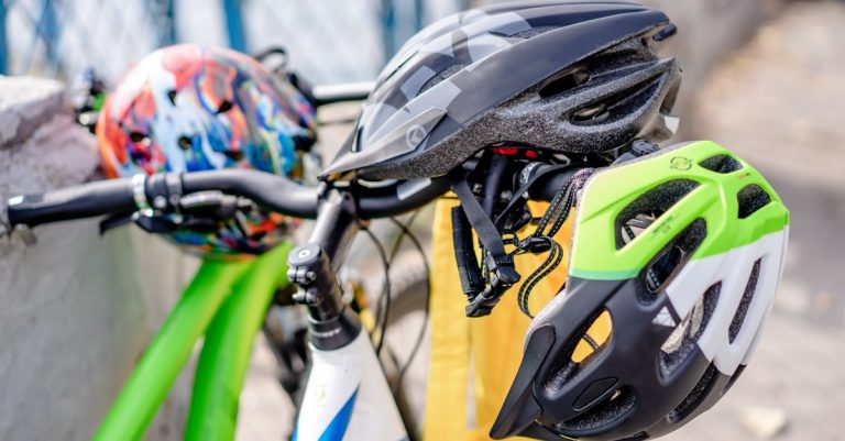 Close-up of brightly colored bicycle helmets resting on bike handlebars, emphasizing safety.