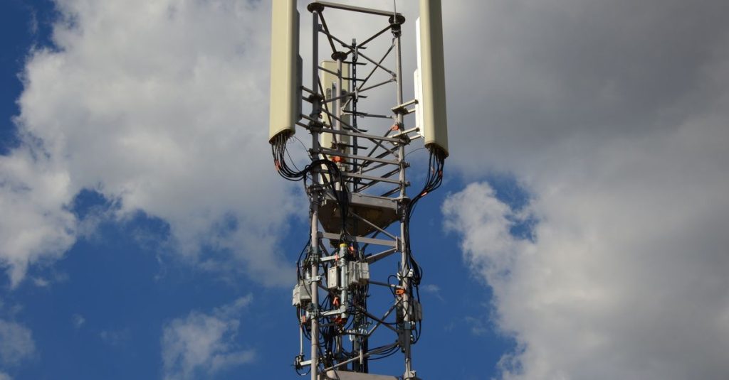 High-angle view of a modern cell tower with technology components against a blue sky with clouds.