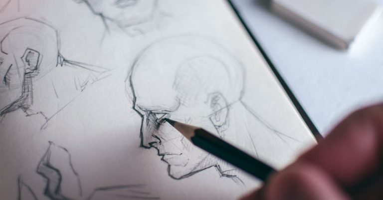 Detailed image of a hand sketching a human face in a sketchbook, emphasizing creativity.
