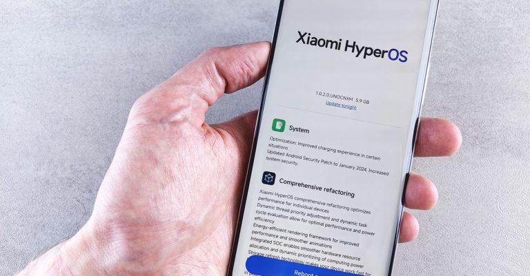 Close-up of a hand holding a Xiaomi smartphone with HyperOS interface, showcasing comprehensive refactoring and system update details.
