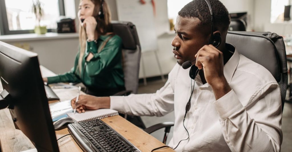 A focused team of customer service representatives working on computers and answering calls in an office