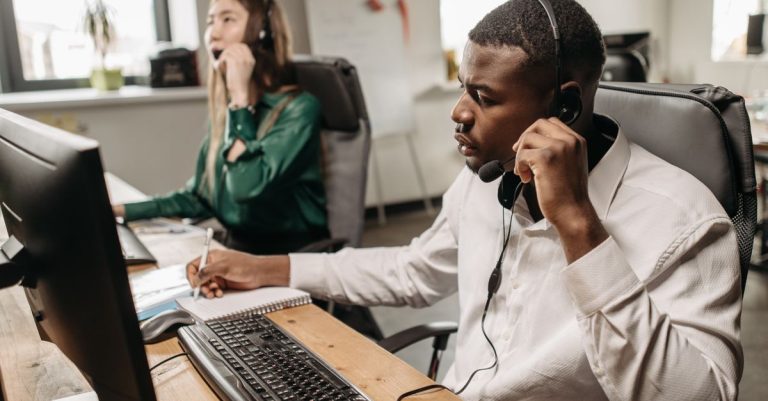 A focused team of customer service representatives working on computers and answering calls in an office