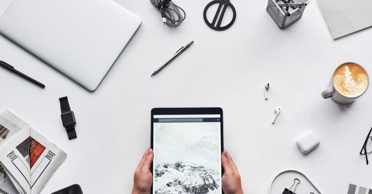 Flat lay of a modern workspace featuring a tablet, gadgets, and coffee for creative work.