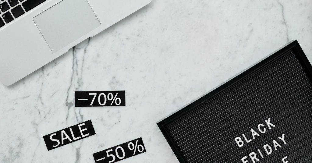 Stylish flat lay showcasing Black Friday sale with discounts on a marble surface.