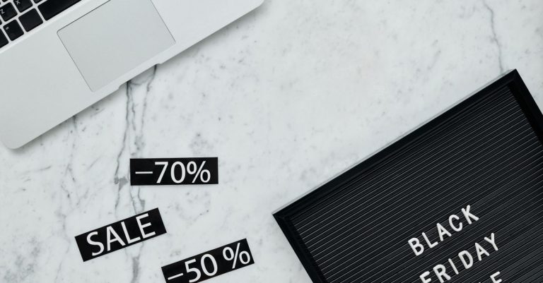 Stylish flat lay showcasing Black Friday sale with discounts on a marble surface.