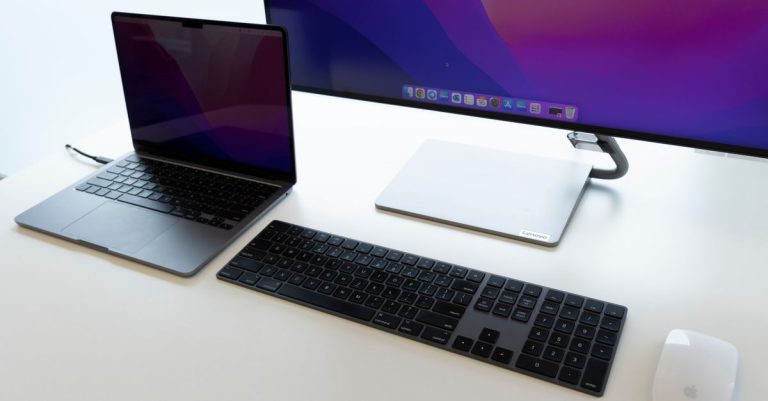 Sleek office desk setup with laptop, keyboard, and monitor for productive work environment.