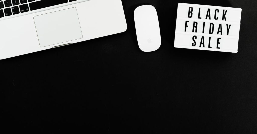 Black Friday sale sign with a laptop and mouse on a black background. Perfect for online shopping promotions.