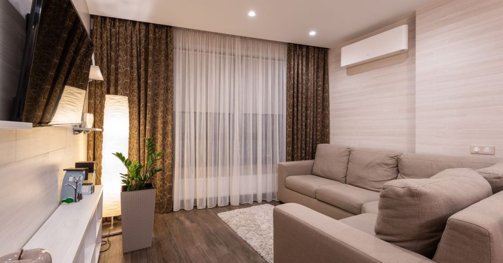A stylish and cozy living room featuring a sofa, wooden flooring, and soft lighting.