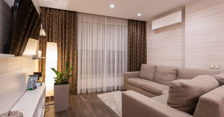 A stylish and cozy living room featuring a sofa, wooden flooring, and soft lighting.