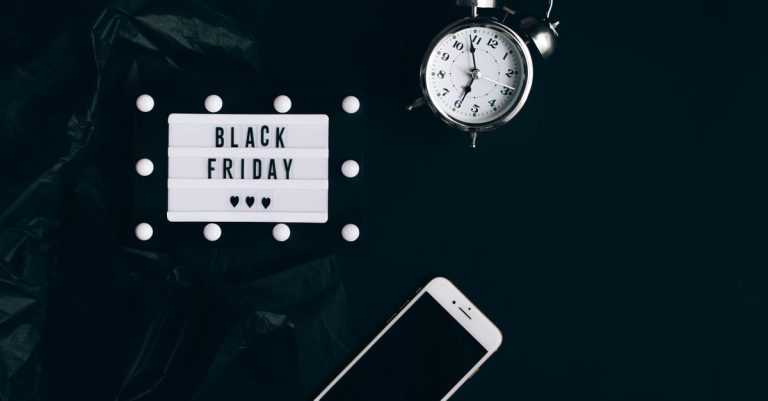 Stylish Black Friday promotion with alarm clock and smartphone on dark background.