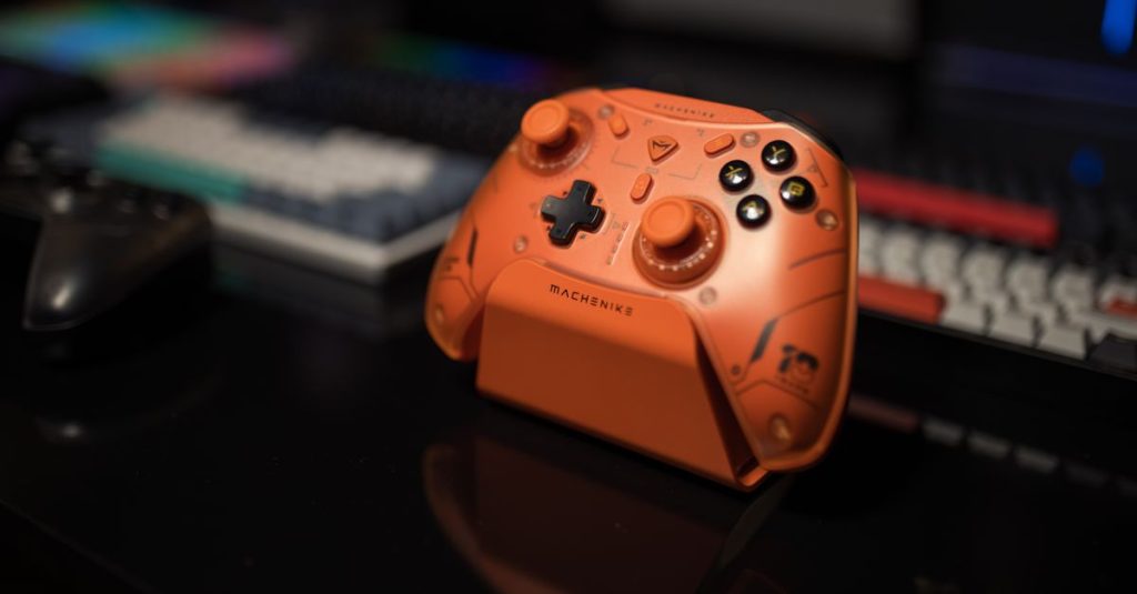 Orange gaming controller on desk with blurred background, ideal for tech enthusiasts.