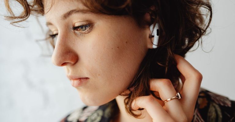 Close-up of a woman with curly hair listening to music using AirPods, showcasing technology and lifestyle.