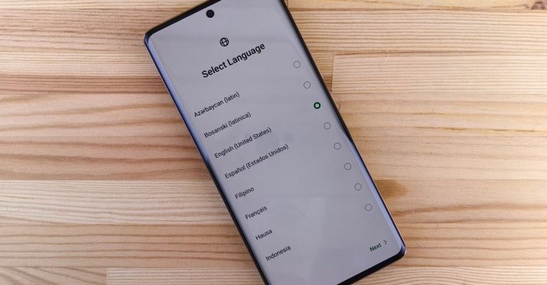 Close-up of smartphone with language selection screen on wooden table.