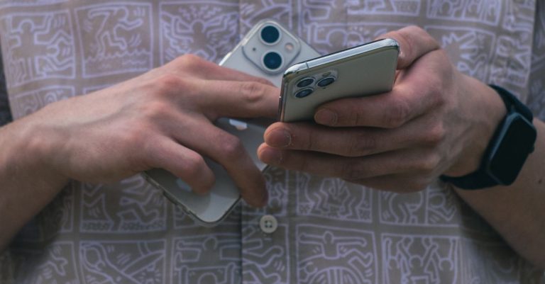 Detail of hands holding two smartphones, showcasing modern technology usage.