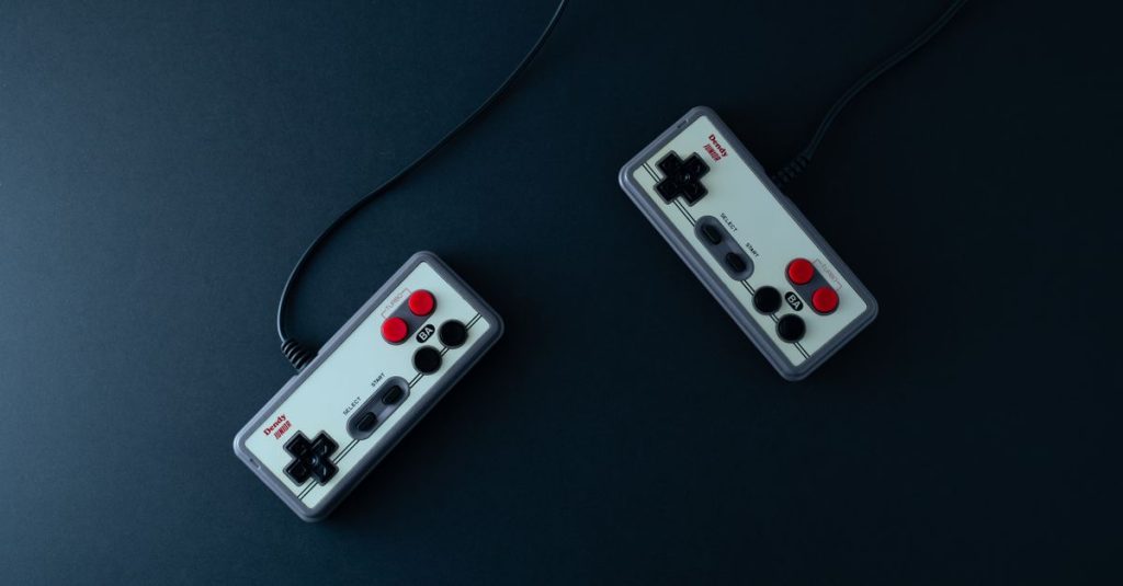 Top view of two retro gaming controllers on a minimalist dark background.
