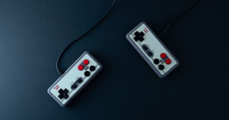 Top view of two retro gaming controllers on a minimalist dark background.
