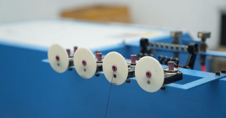 Detailed view of a blue industrial machine with white wheels, highlighting its mechanical parts.
