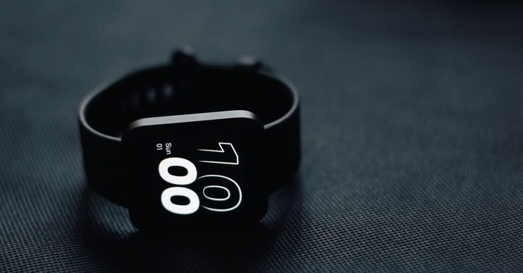 Modern smartwatch displaying time on a sleek dark gray surface, perfect for tech enthusiasts.