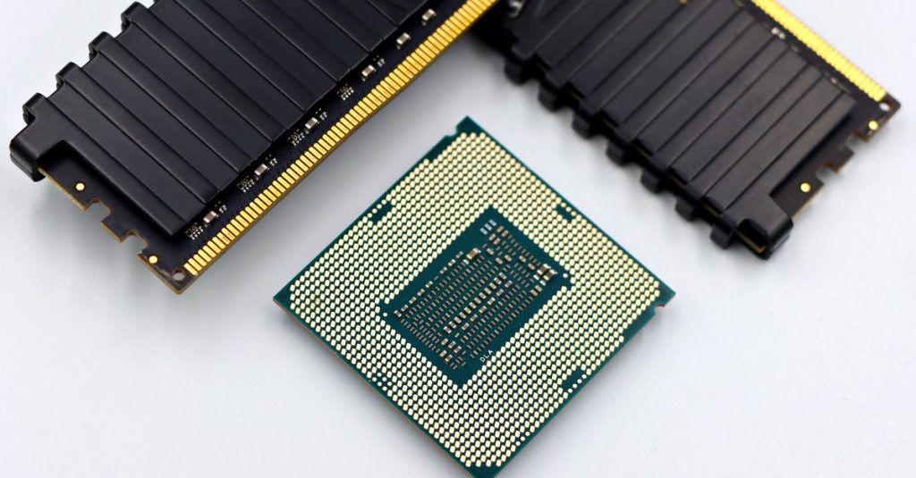 A CPU and RAM sticks displayed on a white surface, showcasing computer hardware components.