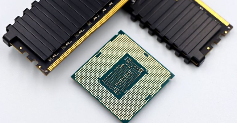 A CPU and RAM sticks displayed on a white surface, showcasing computer hardware components.