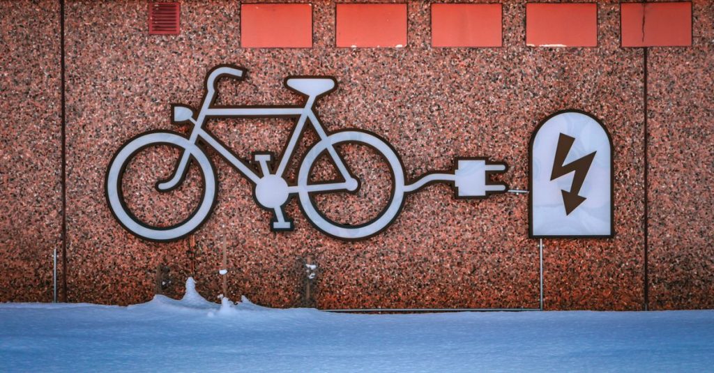 Electric bike charging graphic on a snowy urban wall, promoting renewable energy.