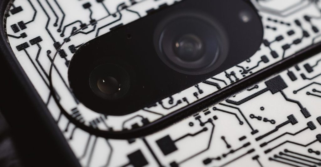Macro shot of an electronic circuit design around a smartphone camera lens, showing intricate details.