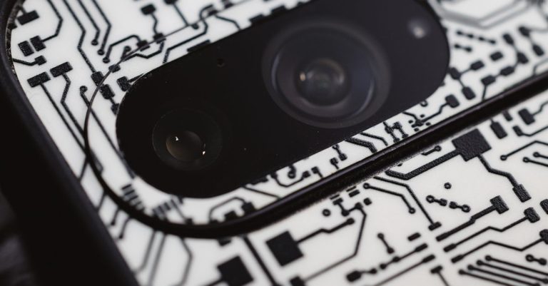 Macro shot of an electronic circuit design around a smartphone camera lens, showing intricate details.