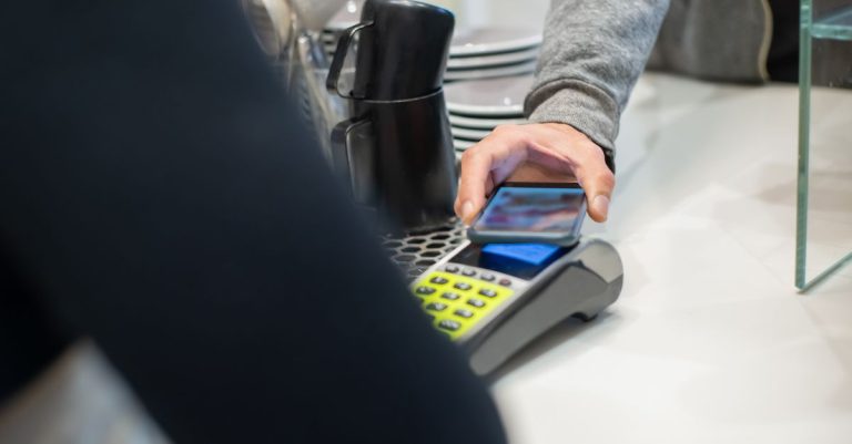 A customer makes a contactless payment using a smartphone at a café, showcasing modern digital transactions.