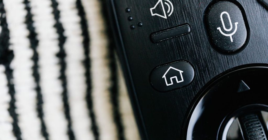 Detailed macro shot of a sleek black remote control with microphone button and textured background.