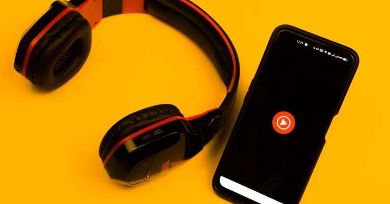 Wireless headphones and smartphone with play icon on a vibrant yellow background.