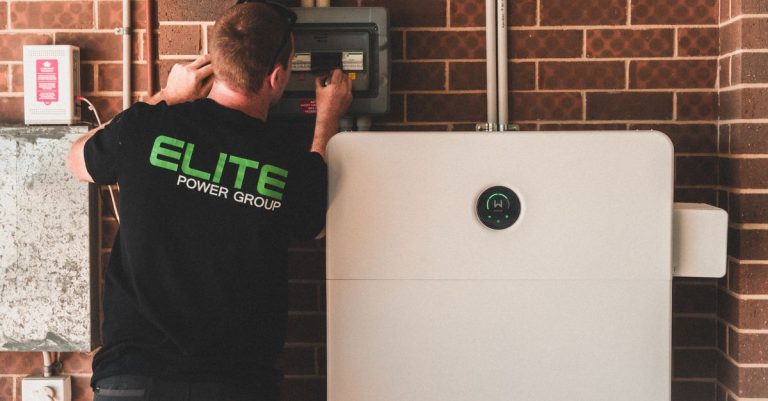 Electrician installing a home energy battery storage unit. Renewable and sustainable energy solution for residential use.