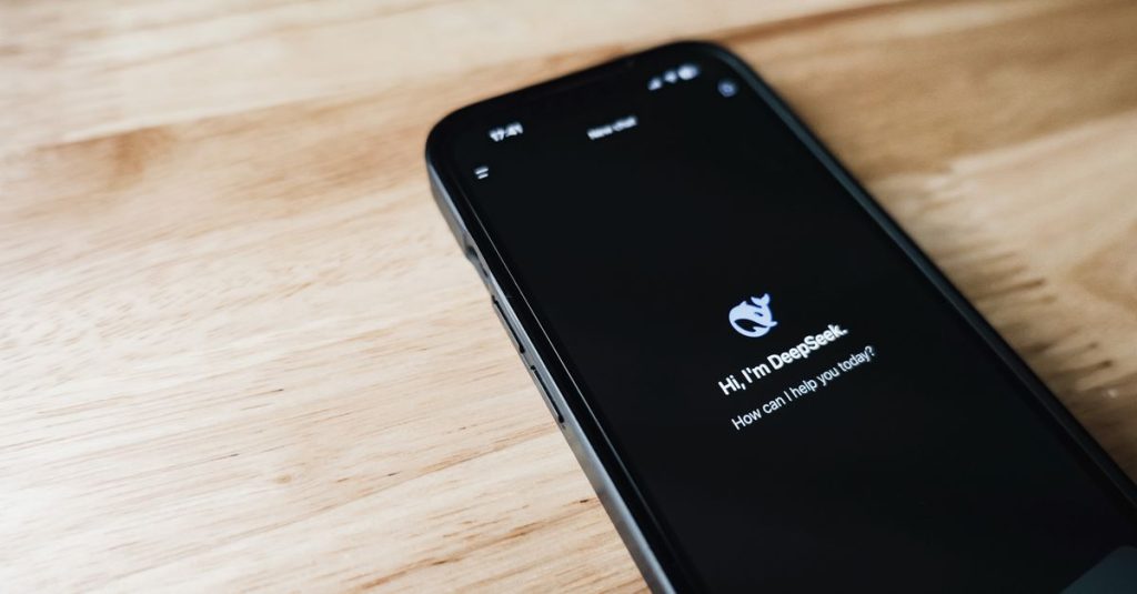 Close-up of a smartphone with DeepSeek virtual assistant on screen, placed on a wooden surface.