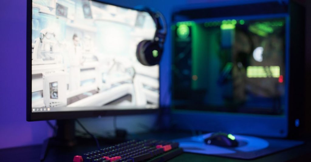 High-tech gaming setup featuring a curved monitor, RGB keyboard, and vibrant lighting.