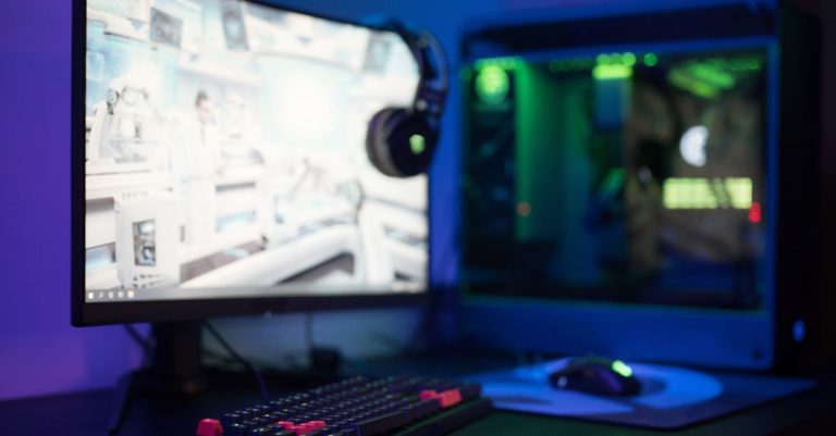 High-tech gaming setup featuring a curved monitor, RGB keyboard, and vibrant lighting.