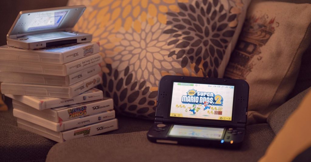 Two handheld gaming consoles on a sofa with game cartridges, creating a cozy game night mood.