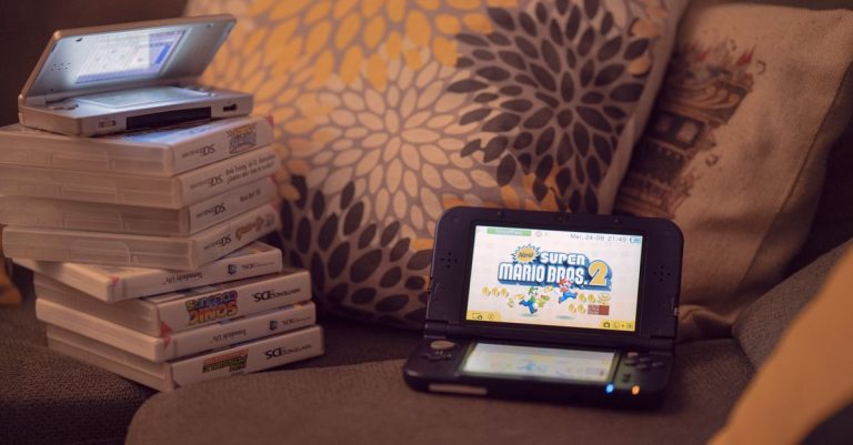 Two handheld gaming consoles on a sofa with game cartridges, creating a cozy game night mood.