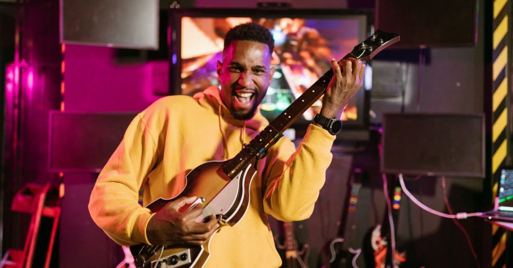 A cheerful adult playing Guitar Hero indoors, exuding excitement and happiness.