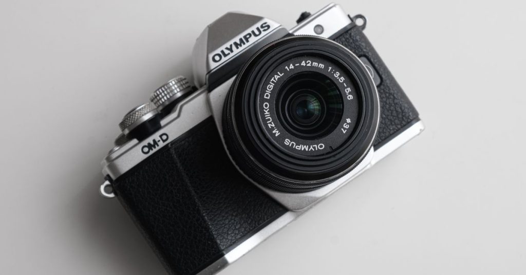 Top view of a vintage Olympus camera with a sleek design on a white background.