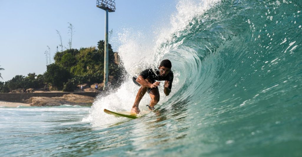 Surfer riding a powerful wave in Rio de Janeiro, capturing thrilling water sports action.
